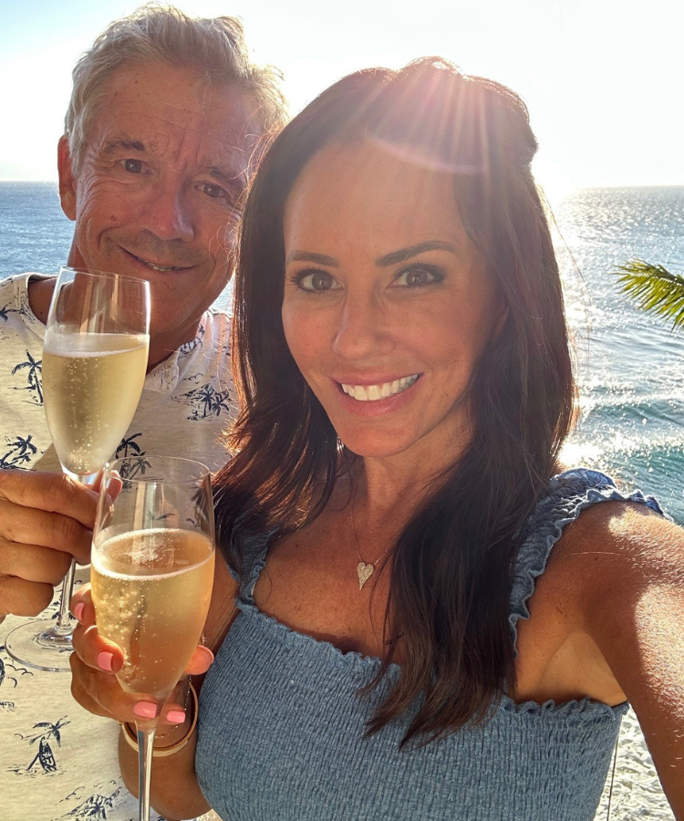 Ron and Lori smiling on Maui beach with champagne glasses