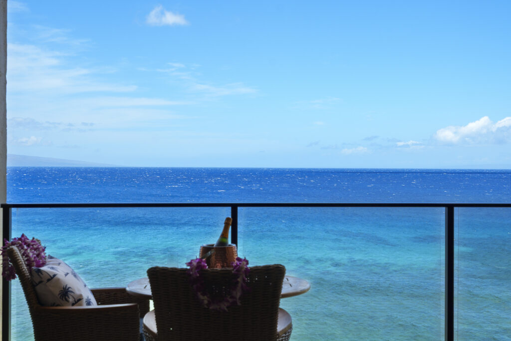 Bright blue sweeping ocean view from patio with outdoor chairs and champagne in ice bucket