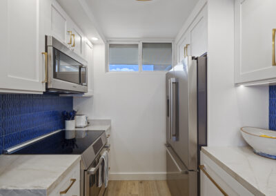 Post-remodel: bright and light modern kitchen with white cabinets, stainless appliances, and blue tile backsplash