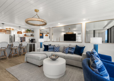 Bright modern living room with off-white sectional and blue chairs and mirrored back wall