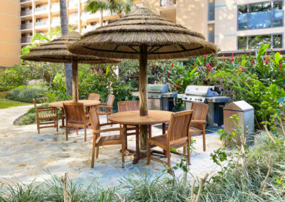 Outdoor eating area with sunchairs, umbrellas, and BBQ grills.