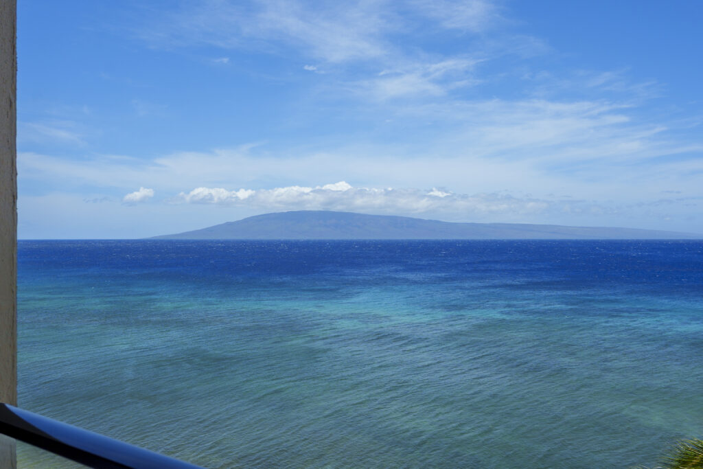 Bright blue sweeping ocean view with outer island of Lanai in distance.