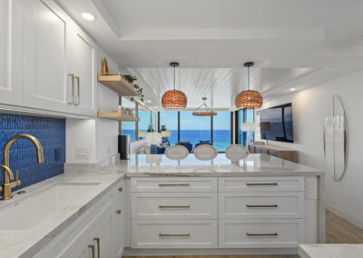 Post-remodel: bright and light modern kitchen with white cabinets, gold hardware, and blue tile backsplash
