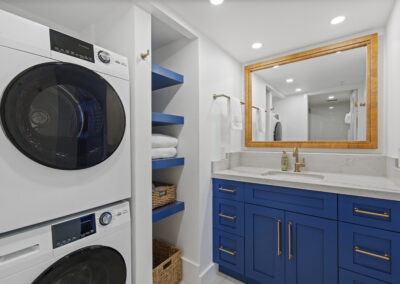 White washer and dryer frontloading stack in bathroom with bright blue vanity
