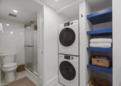 White washer and dryer frontloading stack in bathroom with shelves and storage