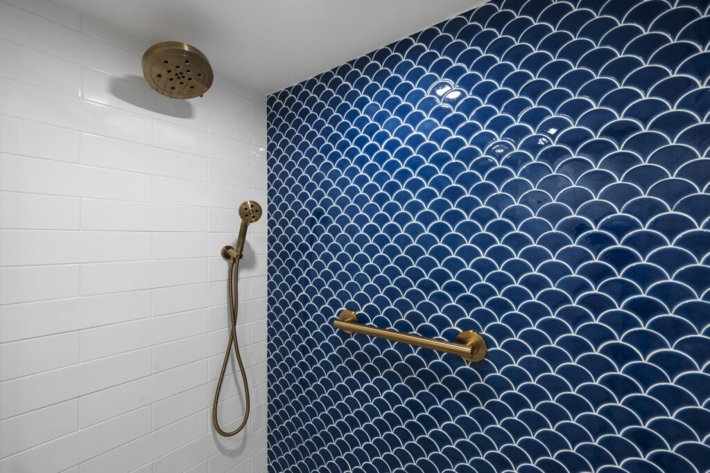 Modern walk in shower with blue and white geometric tiles and gold brushed hardware