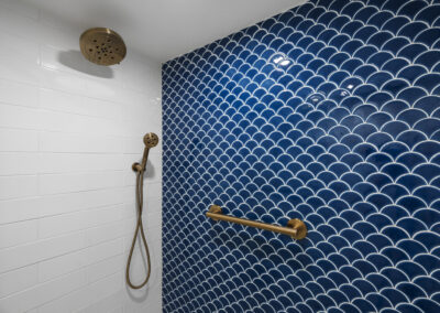 Modern walk in shower with blue and white geometric tiles and gold brushed hardware